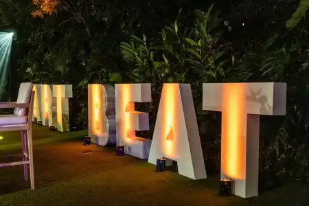 Large illuminated “ART BEAT” letters displayed outdoors among greenery