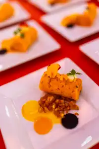 Plated appetizer with sauce, garnish, and edible flower on white dish