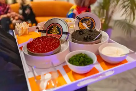 Tray of caviar tins with garnishes, spoons, and condiments at tasting station