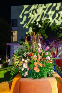 Large floral arrangement outdoors with projected light pattern on building wall