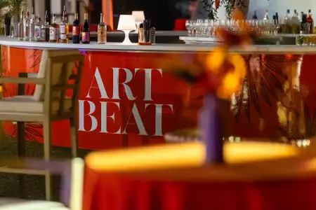 Bar setup with bottles and glassware, “ART BEAT” signage on orange counter