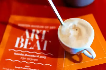 Cup of coffee on “ART BEAT” event card with orange design