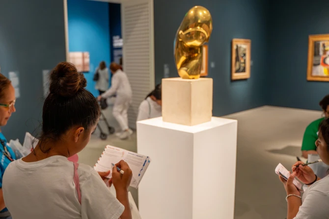 museum guests complete a self directed gallery activity. Observing a sculpture work and writing their observations in a passport styled activity booklet.