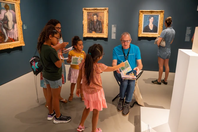 A museum employee helps a group of visitors through an interactive museum experience in the galleries